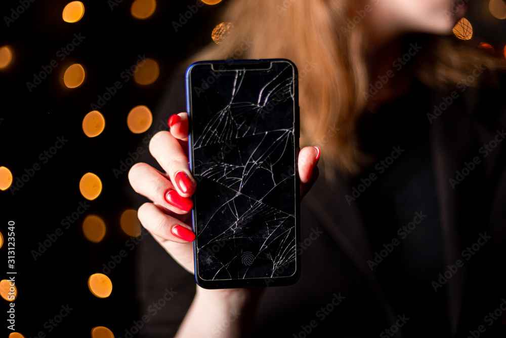 Broken glass screen smartphone in hand of upset girl, white background.